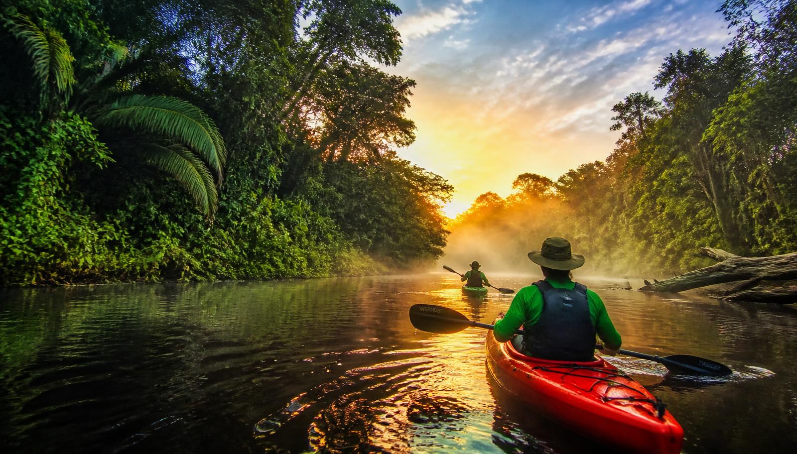 Viajeros navegando en kayak por un río de la Amazonía peruana al amanecer